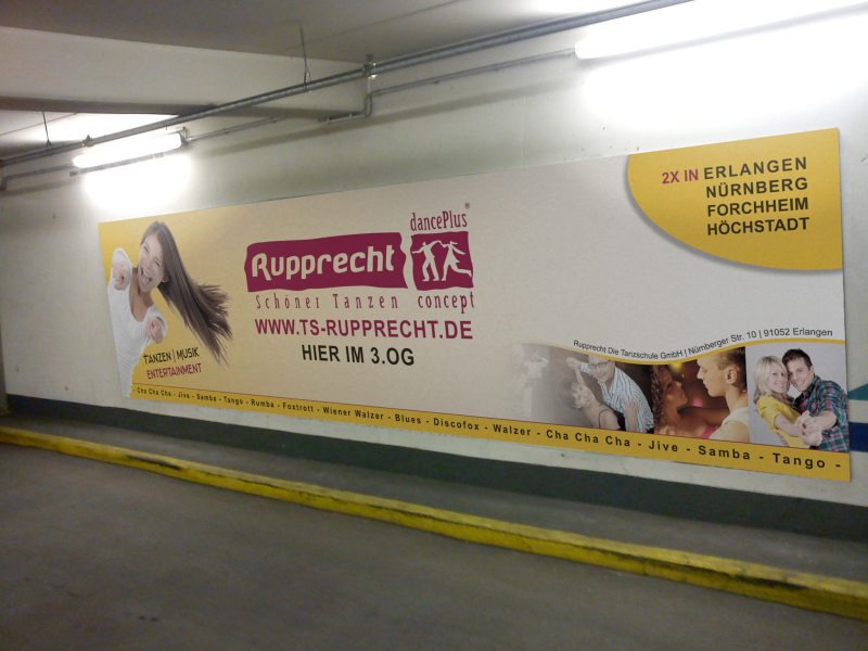 Großformatiges Werbeschild für die Tanzschule Rupprecht in Rot und Gelb, unsichtbar an der Wand befestigt.