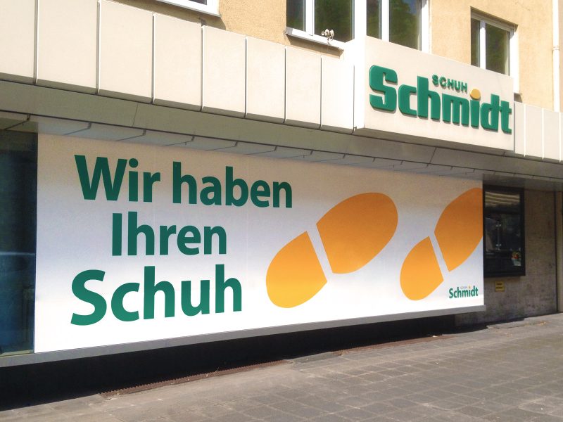Großflächige Sichtschutzbeklebung in der Ladenfront für "Schuh Schmidt" mit orangenen und grünen Akzenten.