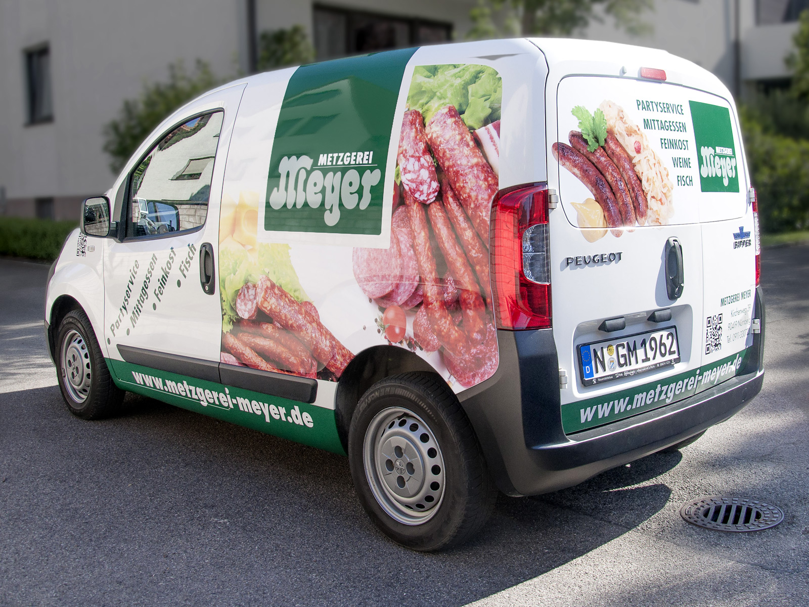 Blick von Hinten auf das Fahrzeug der Metzgerei Meyer im grünen Design mit großflächigen Digitaldrucken.