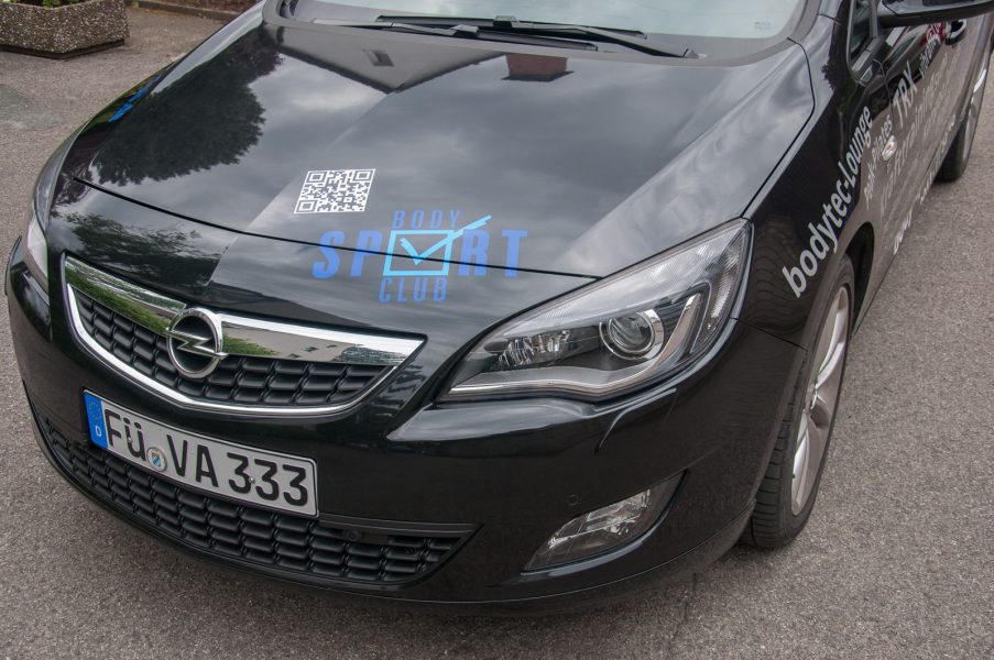 Fronthaube eines schwarzen Opels mit Blauer Folienbeklebung.