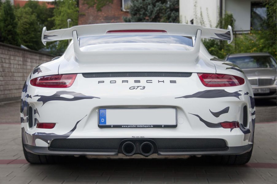 Aufnahme des Hecks des weißen GT3 Porsche im grauem Fetzenlook.
