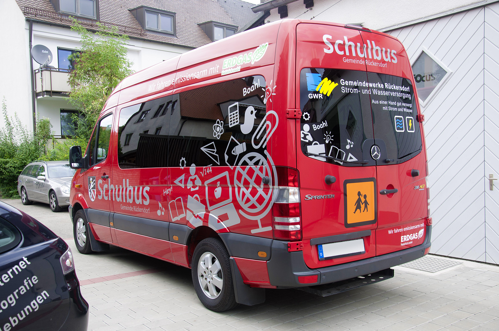 Vollansicht von hinten links, der Folienbeklebung des Schulbusses der Gemeinde Rückersdorf mit grauer Folie.