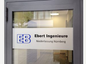 Blaues Logo der "Ebert Ingenieure" mit schwarzer Folienschrift auf grauer Frostfolie als Sichtschutz/Werbung auf einer Glastür.