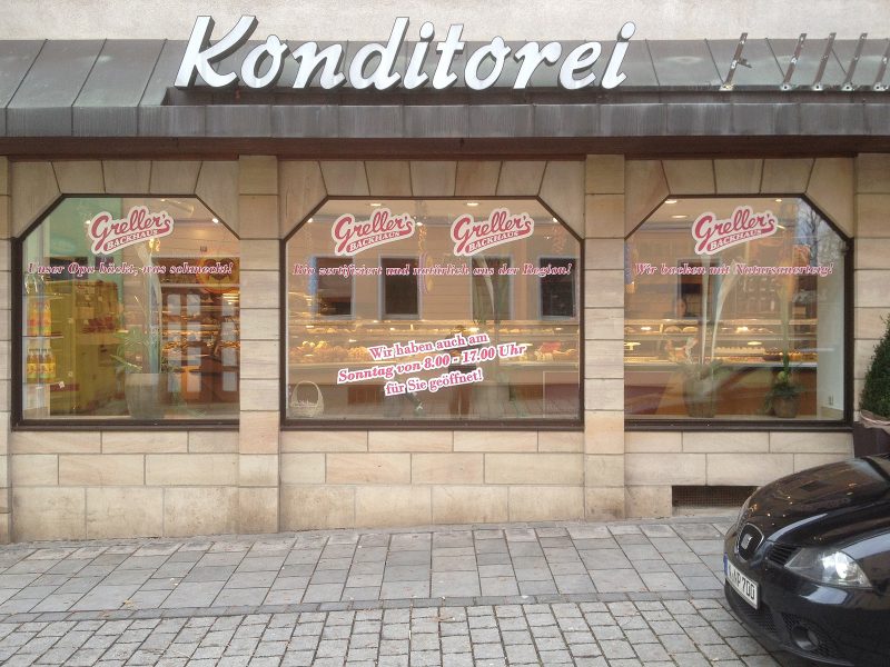 Gestaltete Ladenfront eines Bäckers mit magentafarbener Folienschrift auf einem weißem Hintergrund.