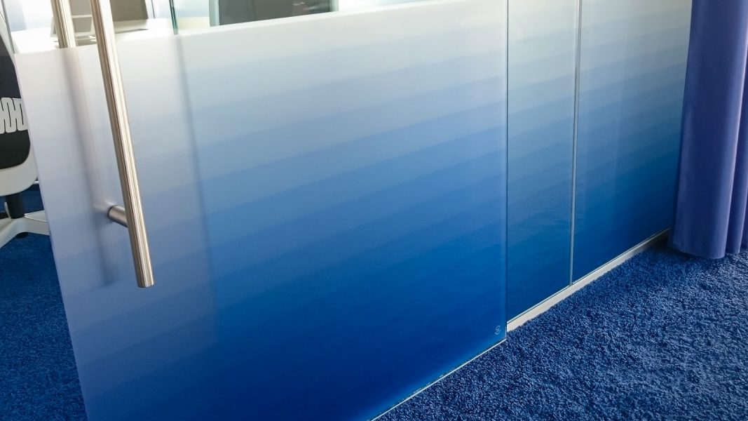 Nahaufnahme der blau bedruckten Milchglasfolie an dem Glasbüro