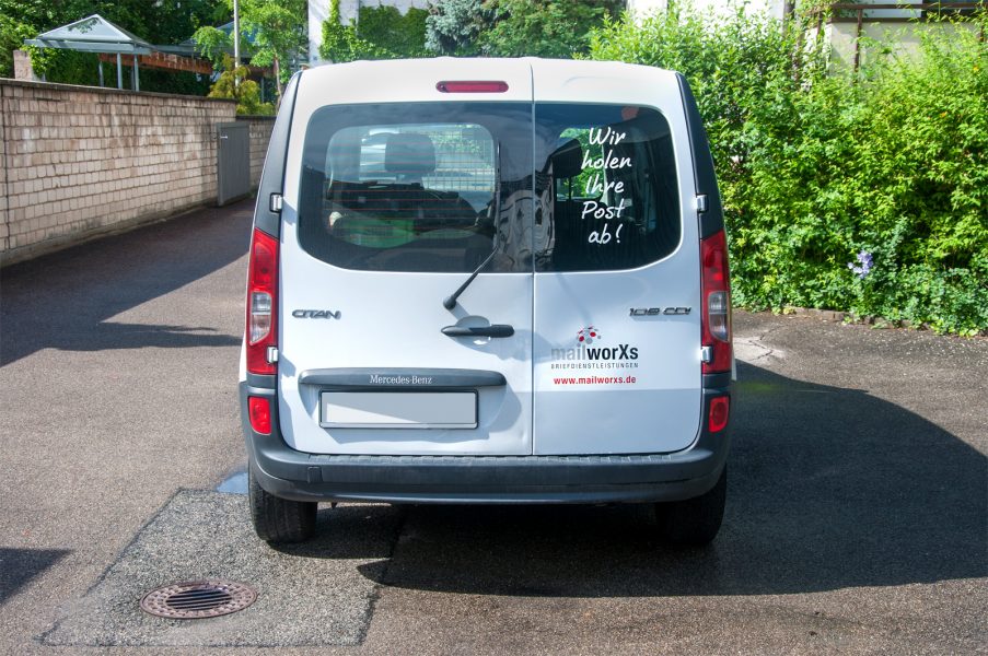 Heckansicht des folierten MailxorXs Fahrzeuges mit dem Slogan "Wir holen Ihre Post ab!"