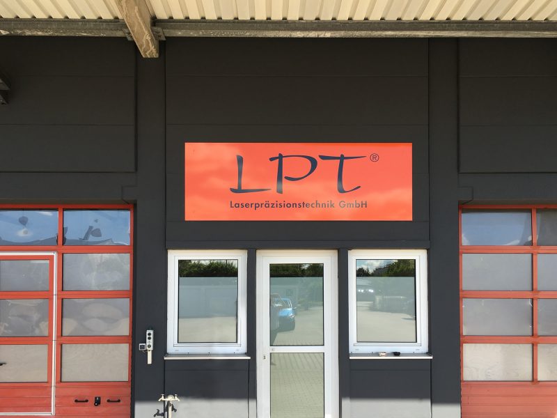 Großes orangenes Schild für den Eingangsbereich der Firma LPT