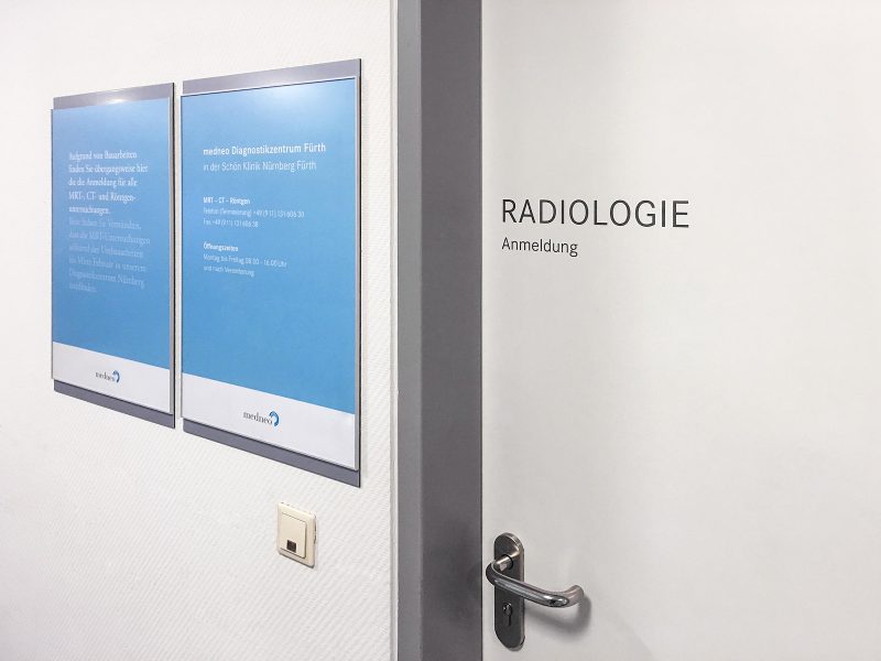 2 Poster an Wand neben dezenter Türbeklebung "Radiologie"