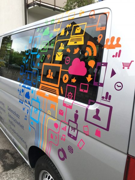 Fahrzeugbeklebung für Brunner und Schmidt - Detailansicht der farbigen Icons auf dem silbernen VW-Bus