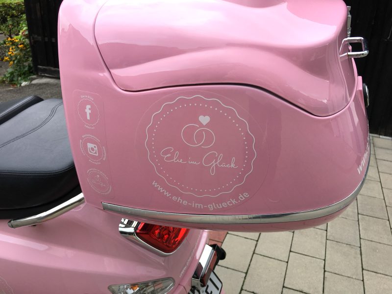Rosa Roller Koffer mit Aufklebern für Ehe im Glück