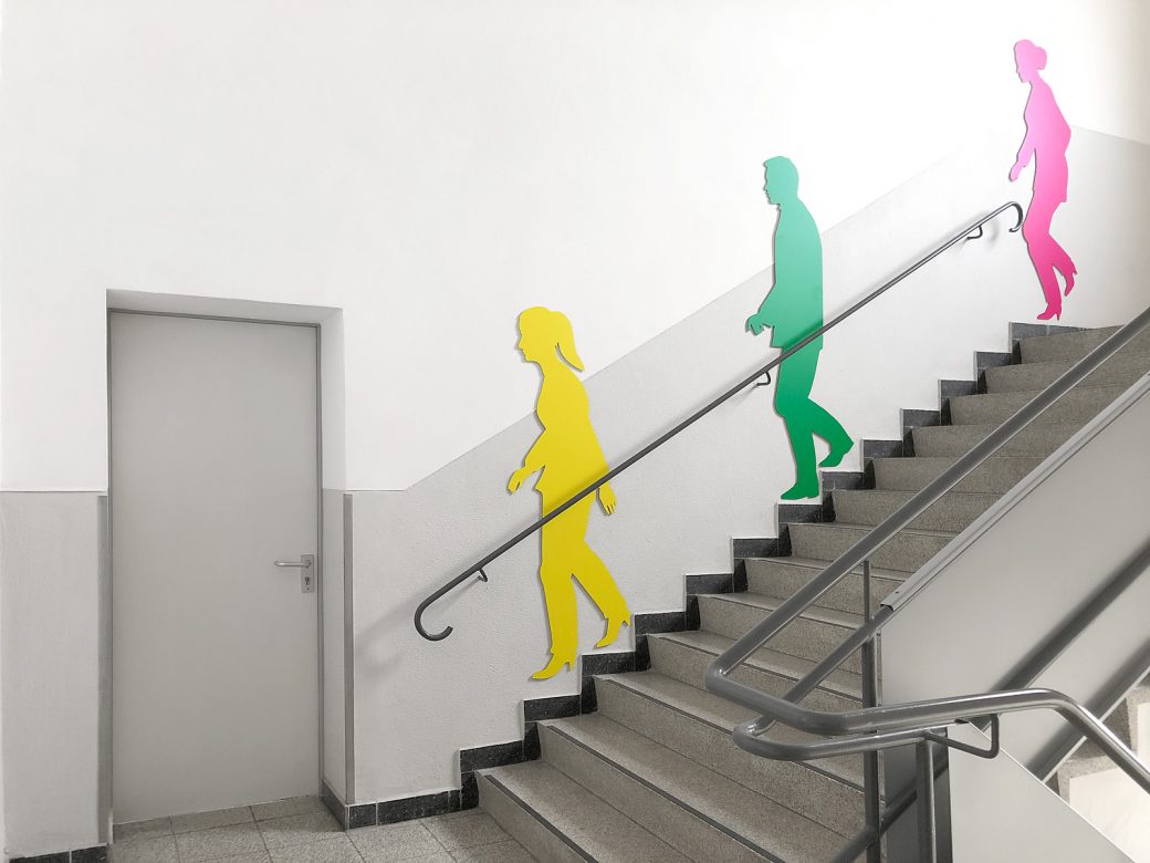 Drei Schattenfiguren in unterschiedlichen Farben an der Wand montiert in einem Treppenhaus bei Siemens