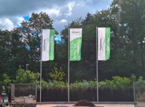 Drei Fahnen mit Masten die auf der Anlage von Garten- und Landschaftsbau Hofmann stehen