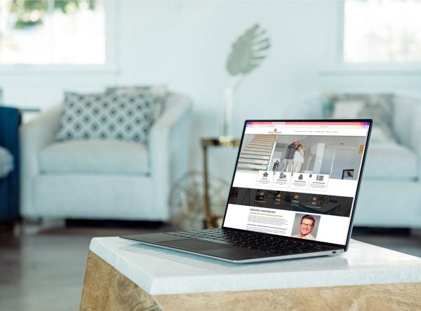 Die Webseite von Skimina Immobilien in einem Laptop an einem gemütlichen Wohnzimmerplatz sichtbar