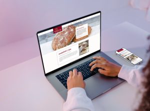 Die Webseite der Bäckerei und Konditorei Backhaus Wirth auf einem Laptop und am Smartphone an einem gemütlichen Arbeitsplatz