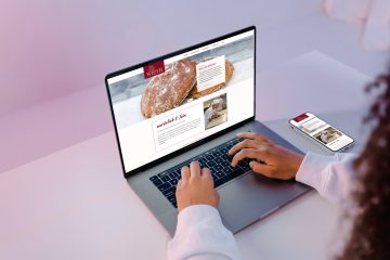Die Webseite der Bäckerei und Konditorei Backhaus Wirth auf einem Laptop und am Smartphone an einem gemütlichen Arbeitsplatz